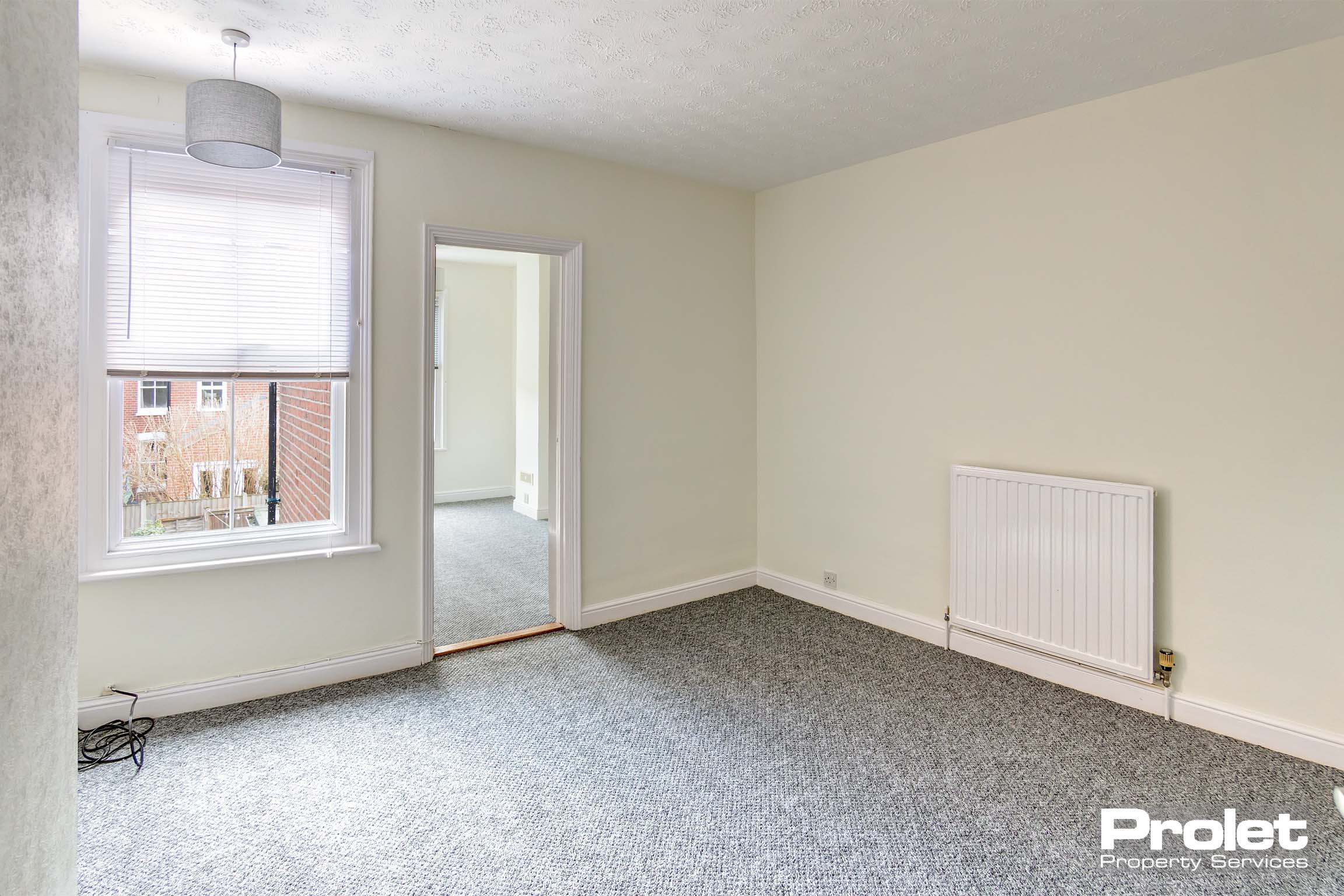 Double bedroom with cream walls and grey carpet. Leads to study