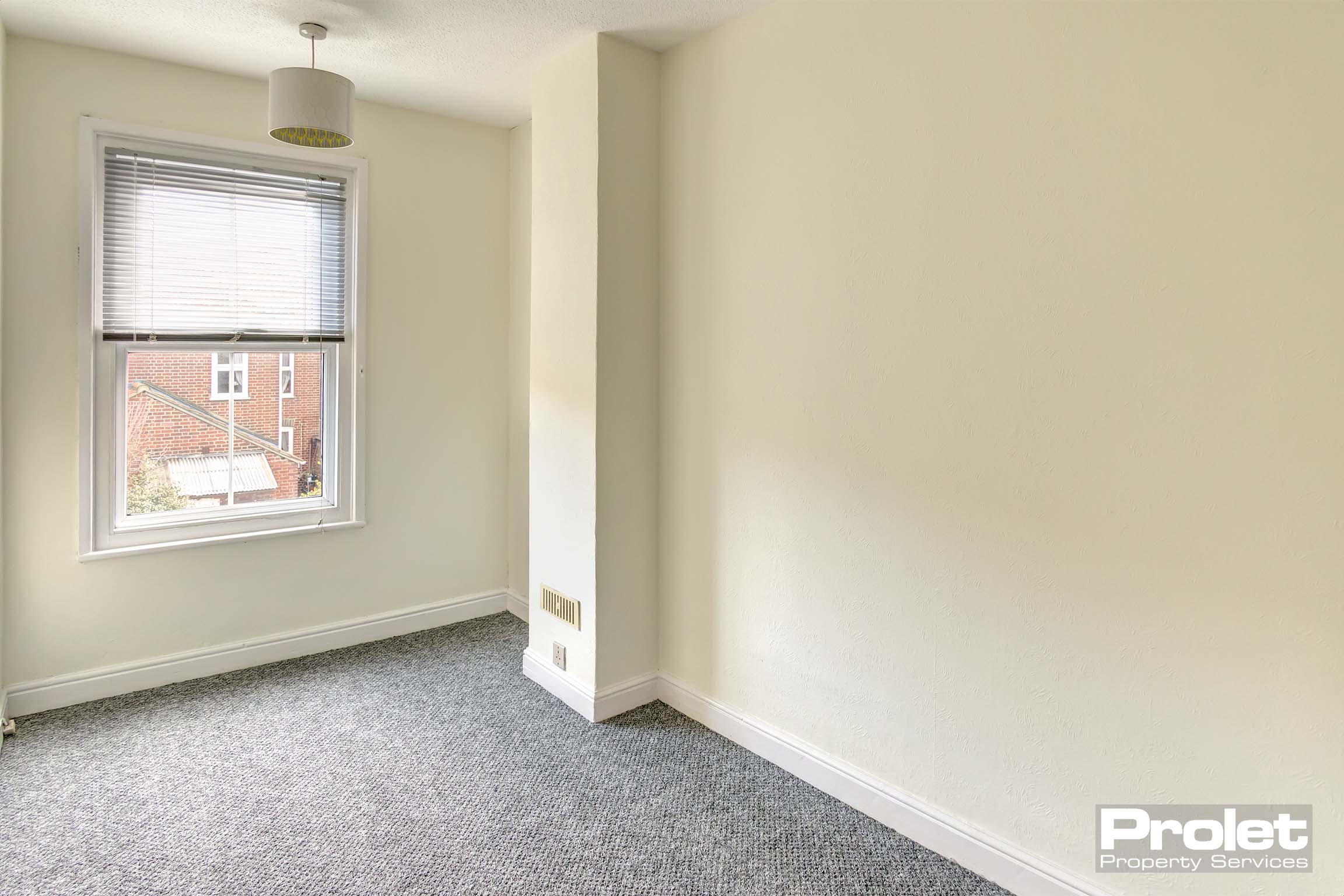 Study with cream walls and grey carpet.