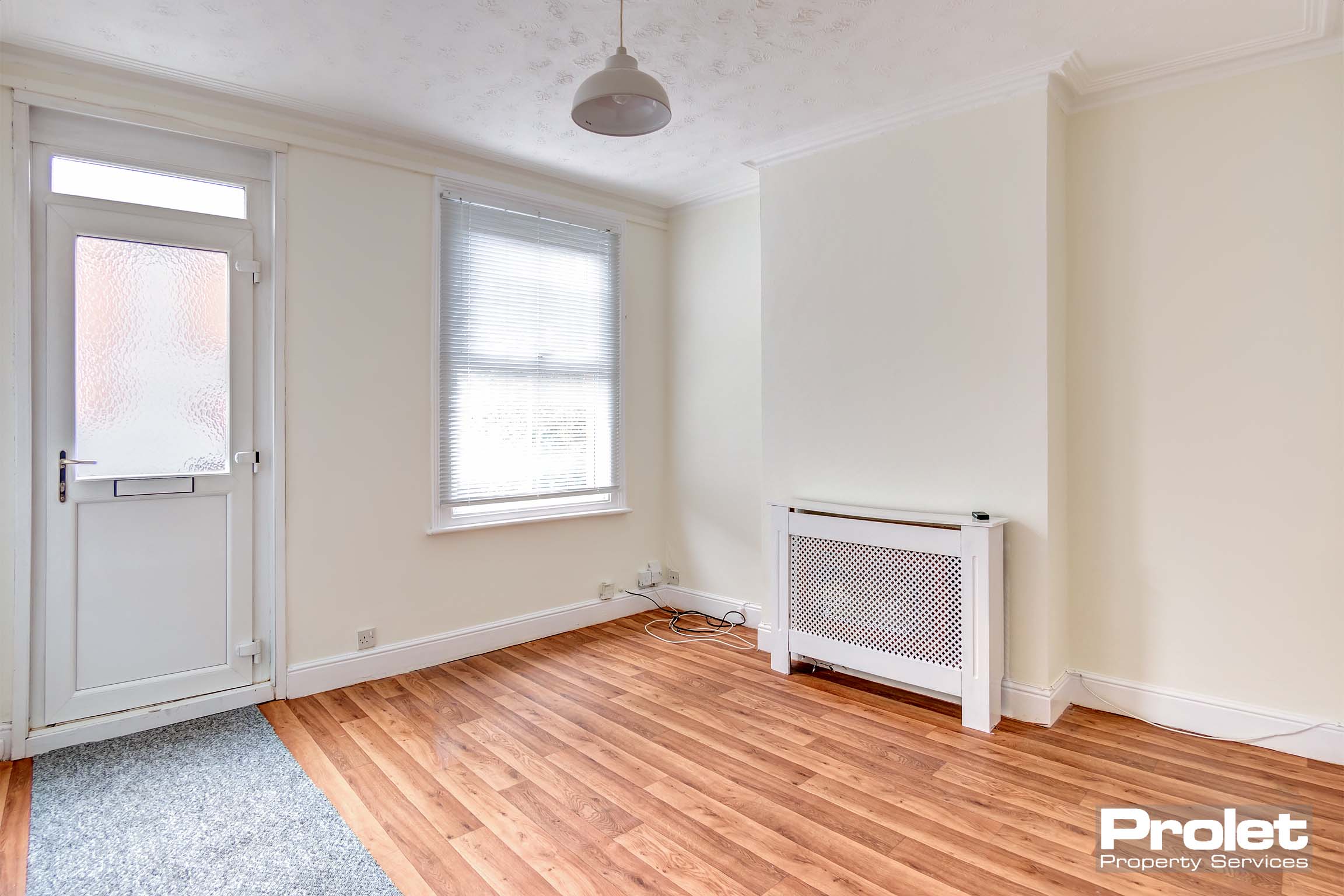 Living room with cream walls, and wood effect lino flooring