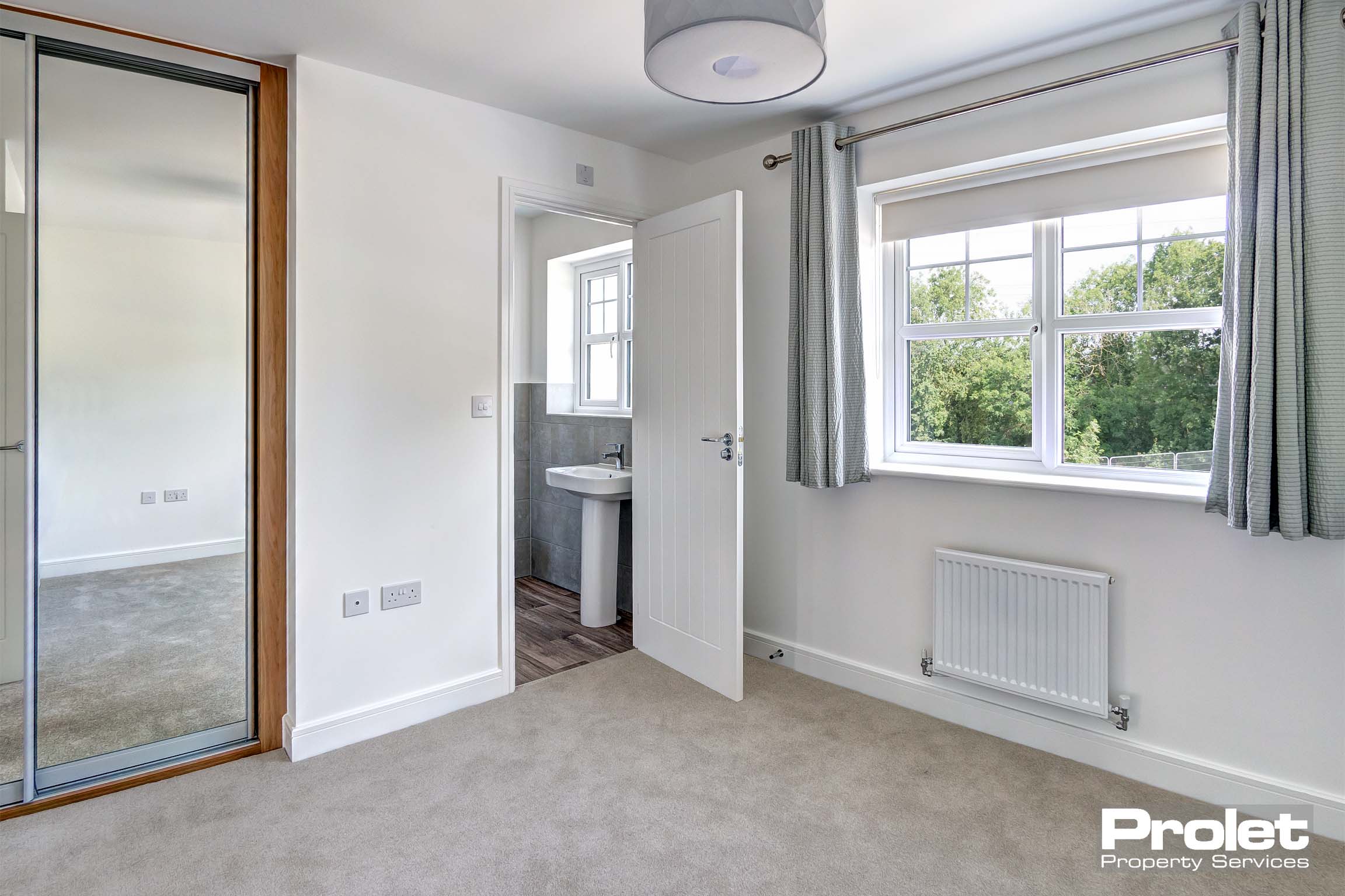 Off white walls with grey carpet, curtains and shades. ensuite.