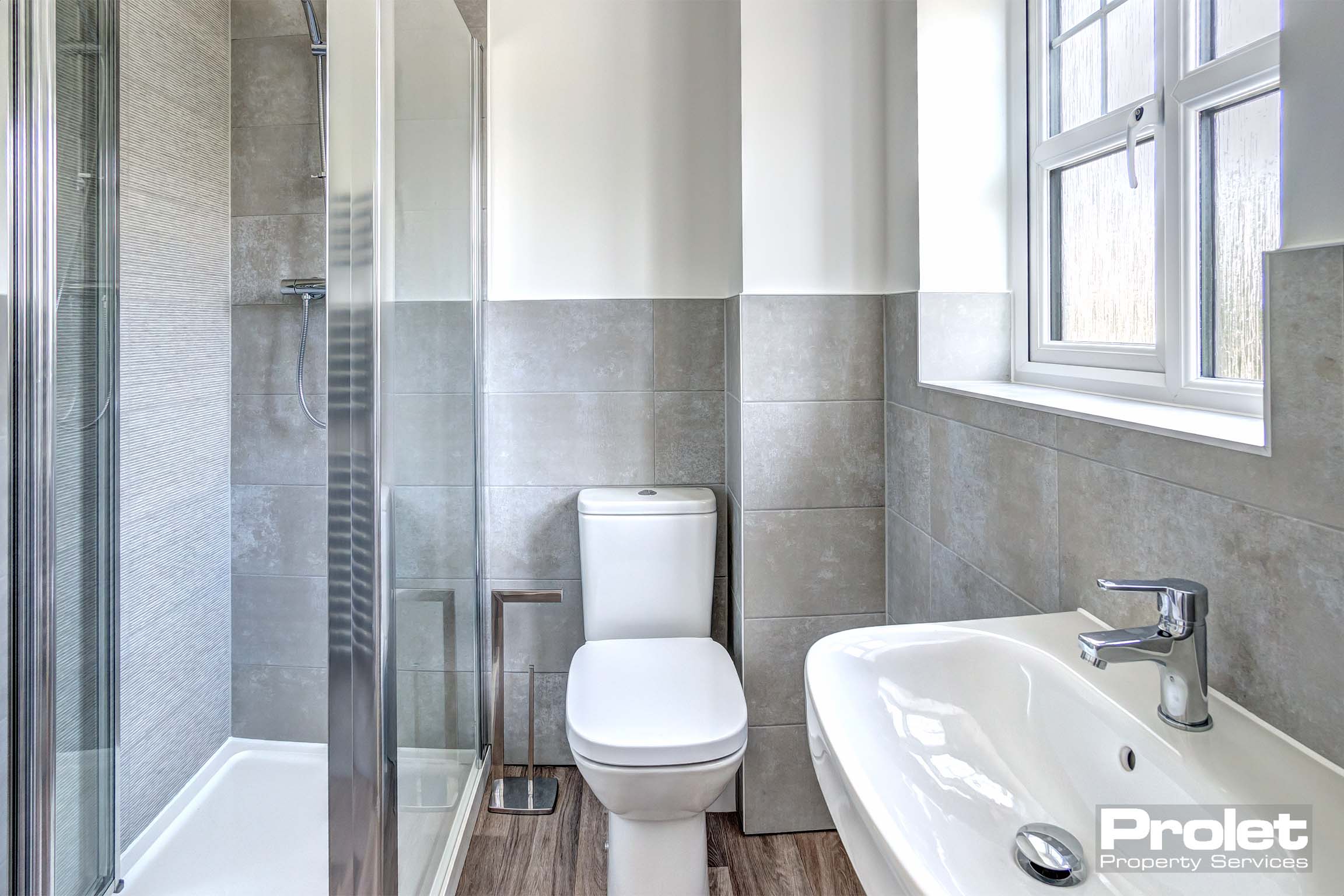 Painted white walls with grey tiles and white suite