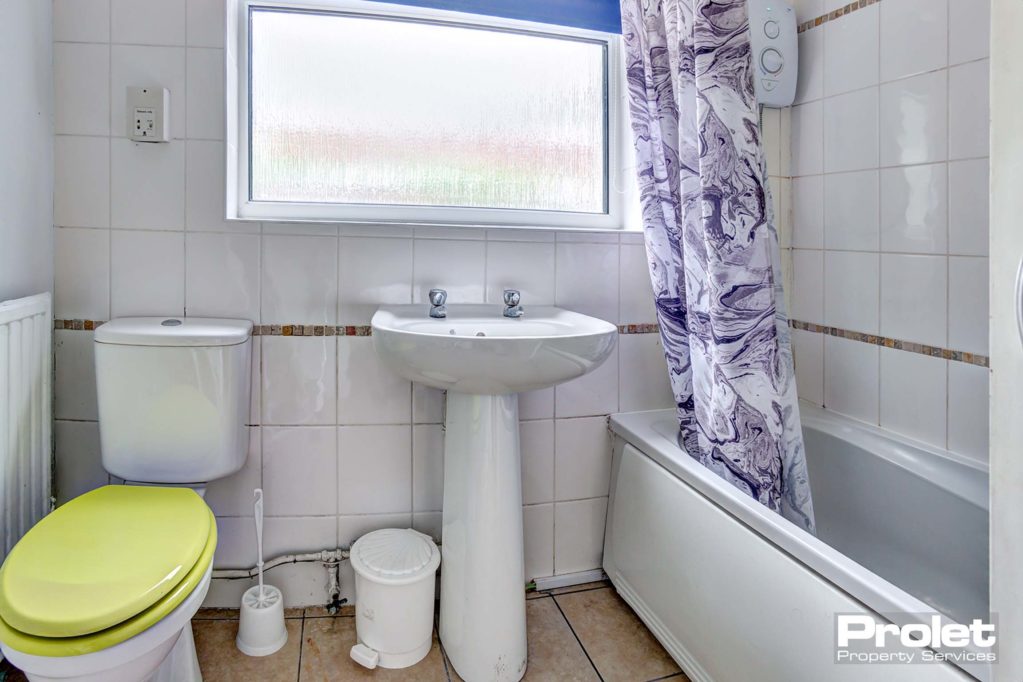 Downstairs bathroom, toilet, sink, and shower over bath