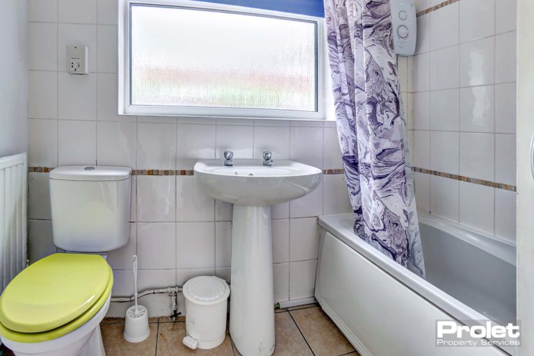 Downstairs bathroom, toilet, sink, and shower over bath