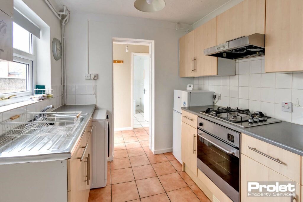 Terracotta floor tiles, oven, washing machine and fridge freezer leading to rear lobby