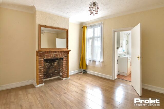 Magnolia walls with laminate flooring and feature fireplace with door to kitchen and