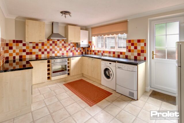Large open kitchen with dining area. Terracotta /beige and rust coloured wall tiles with cream floor. Beech affect units and black worktops.