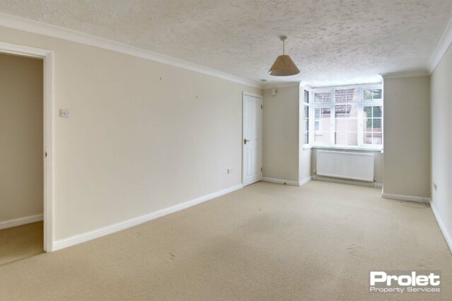 Large lounge with bay window. Magnolia walls and cream carpet.
