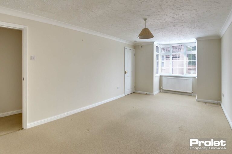 Large lounge with bay window. Magnolia walls and cream carpet.