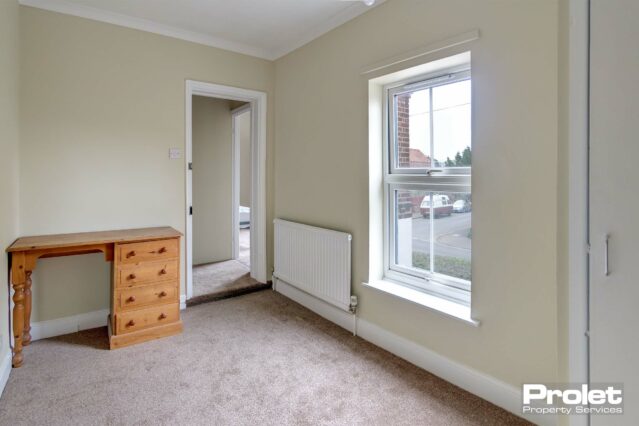 Single bedroom with dressing table and storage cupboard with rail.