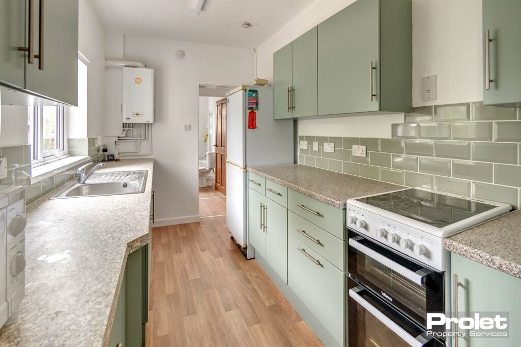 Wooden affect floor with new kitchen units, oven, washing machine, microwave and fridge freezer