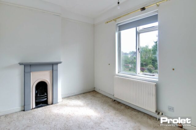 Cream carpet with white walls. Feature fireplace with grey surround