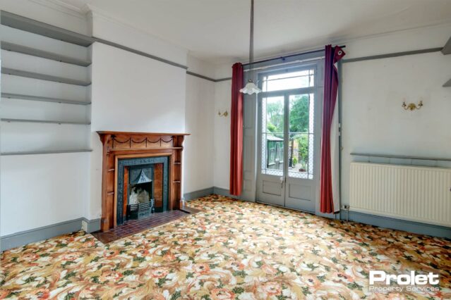 White walls with grey woodwork, feature fireplace and double doors to rear garden.