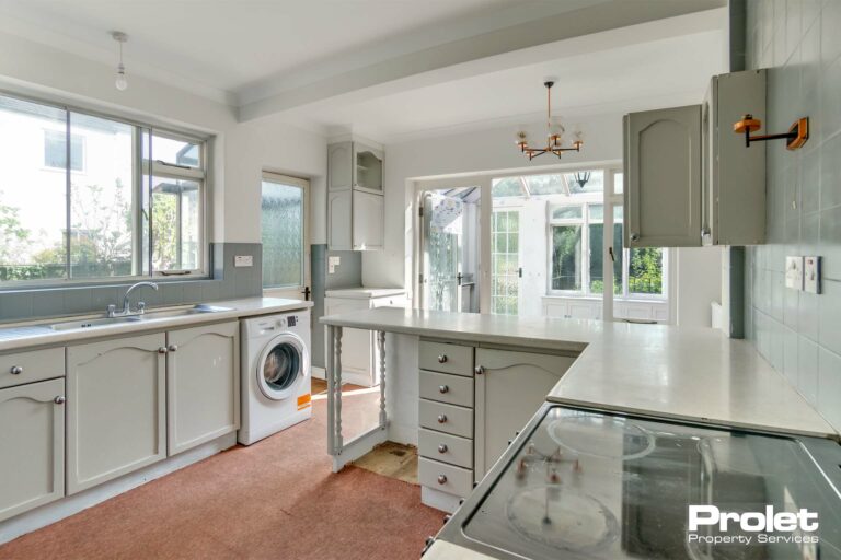 Cream worktops and units with silver handles. Peach carpet. Oven, washing machine and tumble dryer