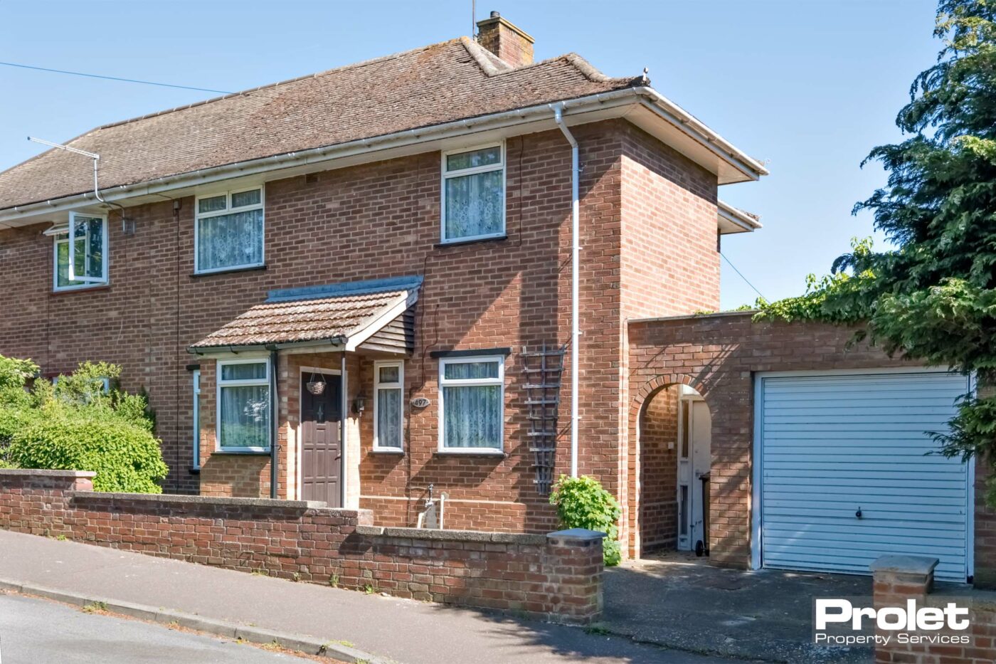 Red brick house with porch, brick walled front and garage attached to the property.property but