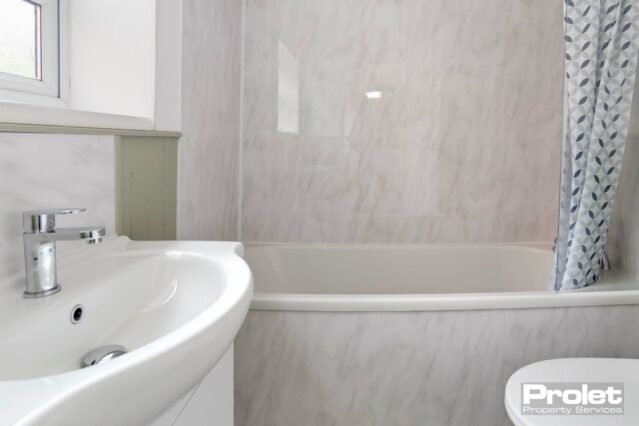 Bathroom with shower over bath, toilet, and sink