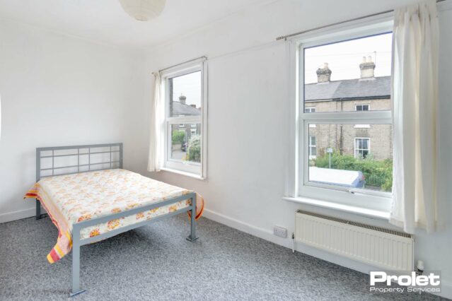 Double bedroom with two windows, grey carpet, and double bed