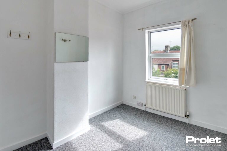 Double bedroom with mirror, coat hooks, grey carpet, and white walls