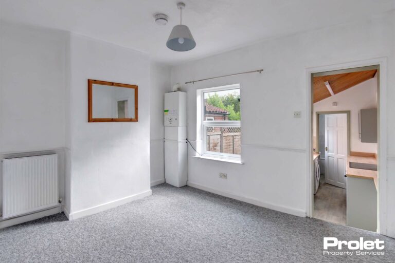 Dining room, leading to kitchen, with white walls and grey carpet