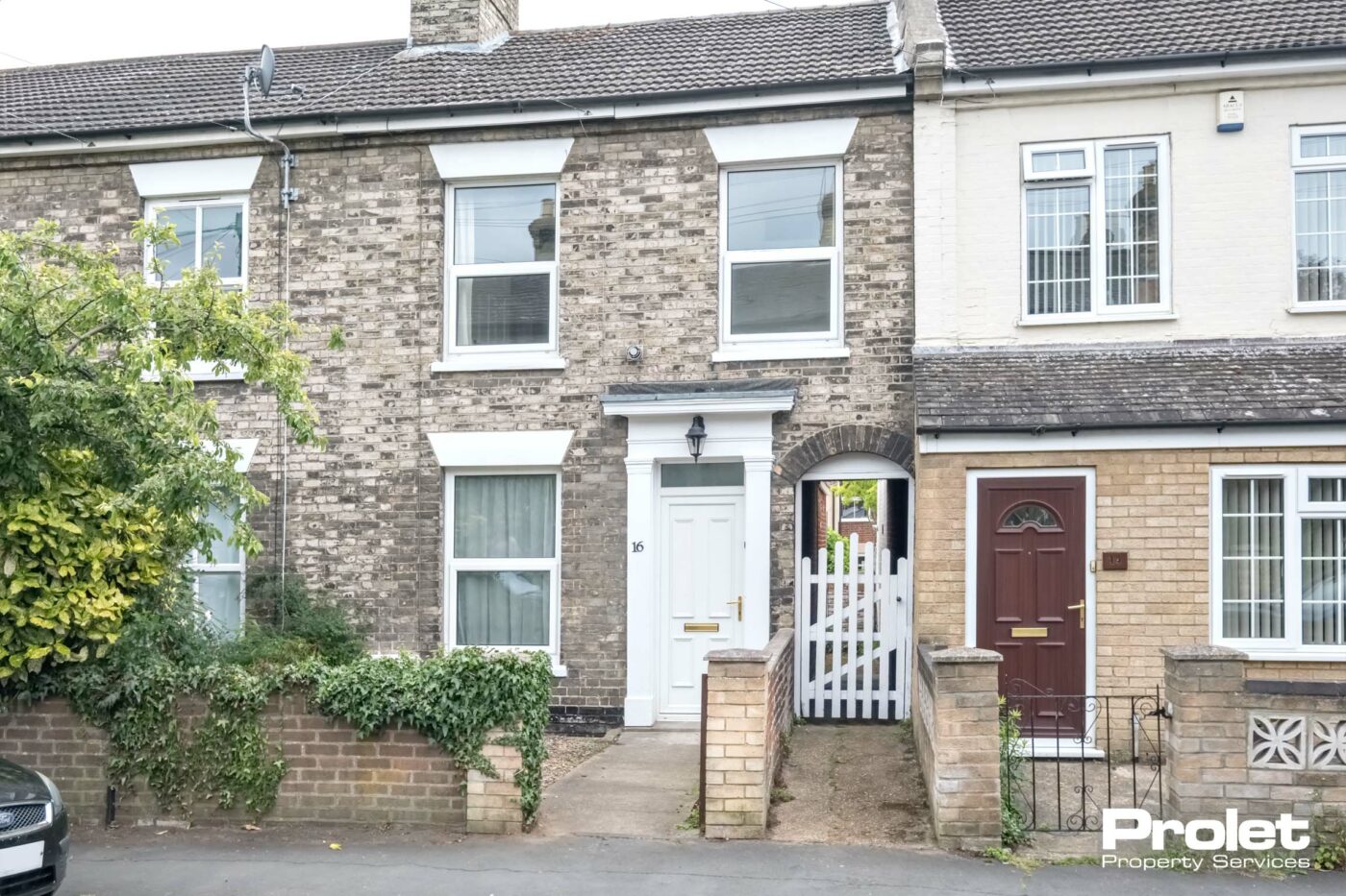 Grey brick terraced house with white front door