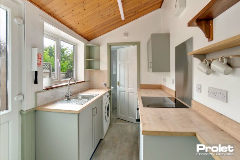 Cottage style kitchen with wood worktops, pale green cabinets, and induction hob