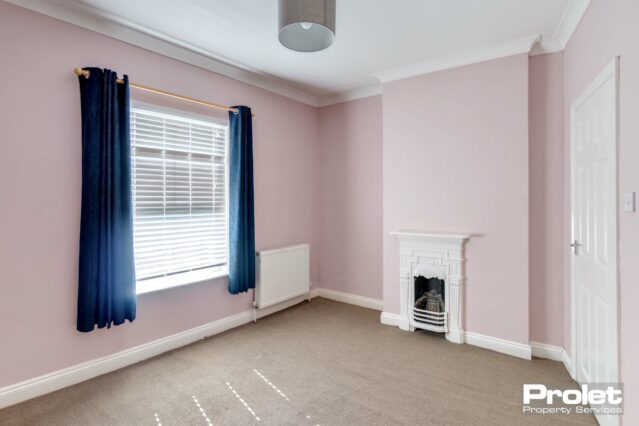 Double bedroom with pink walls and white period fireplace