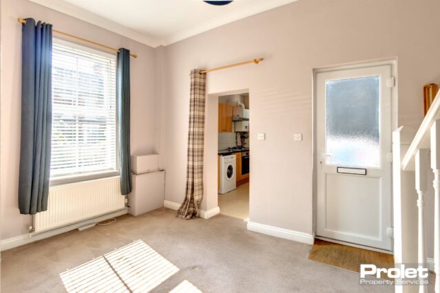 Dining area with pink walls, leading to kitchen