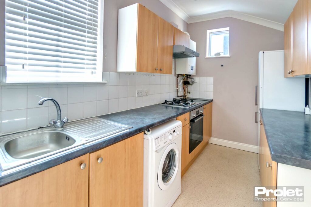 Fitted kitchen with wood effect cabinets and black worktop,