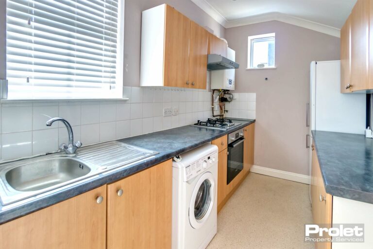 Fitted kitchen with wood effect cabinets and black worktop,