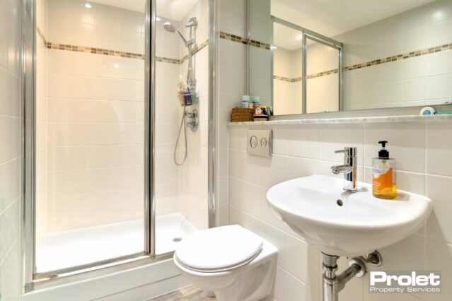 White tiles and laminate flooring with white toilet, sink and shower cubicle