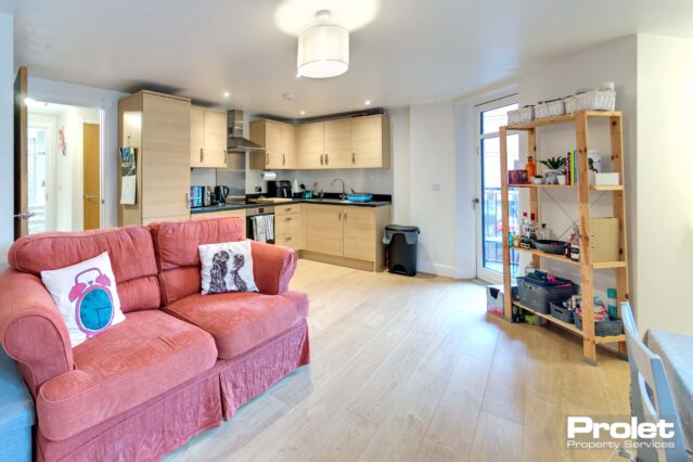 laminate flooring and off whoite walls with sofa, dining set and kitchen with appliances