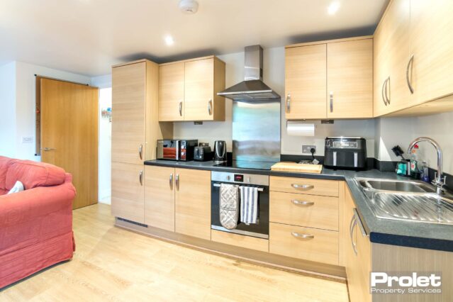 Laminate florring with beech effect units and black top. Integrated appliances