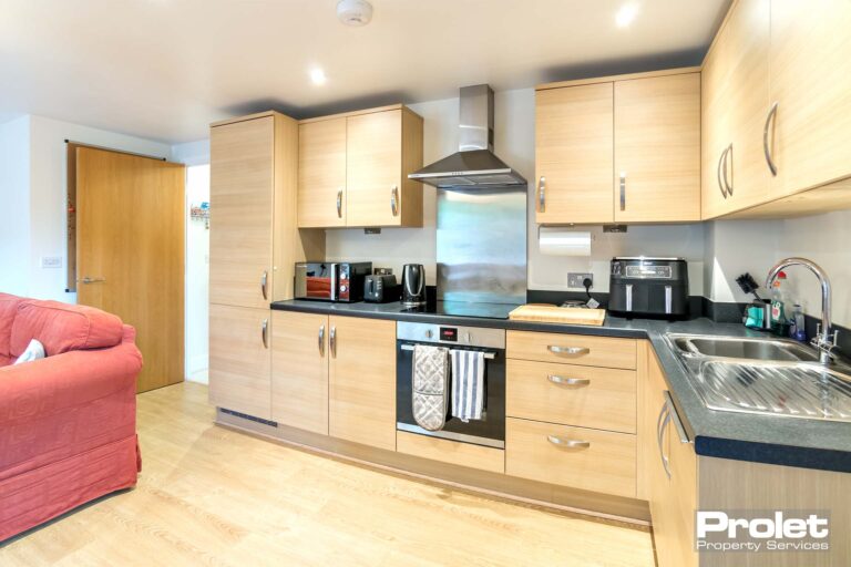 Laminate florring with beech effect units and black top. Integrated appliances