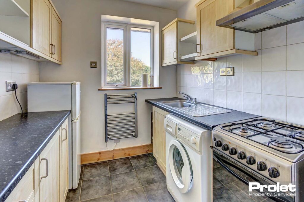 White tiled walls & grey flooring with oven, washing machine and fridge freezer