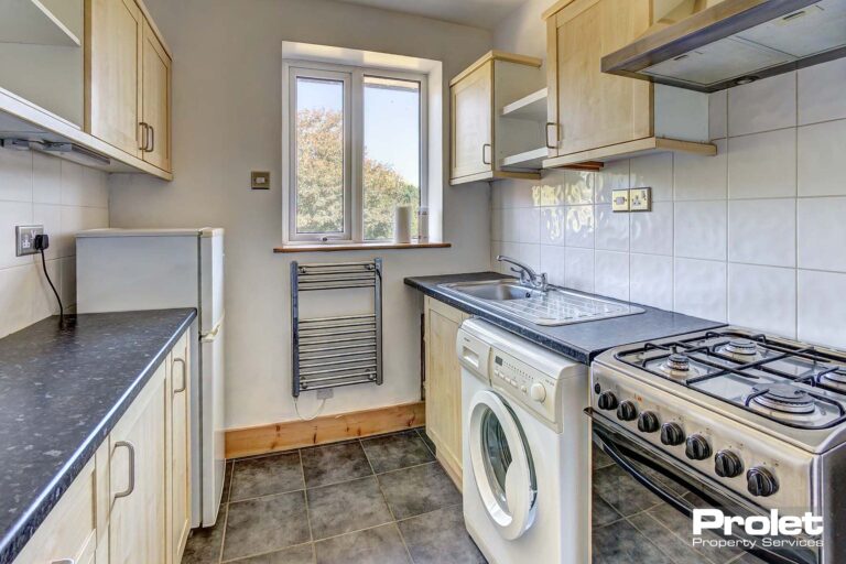 White tiled walls & grey flooring with oven, washing machine and fridge freezer