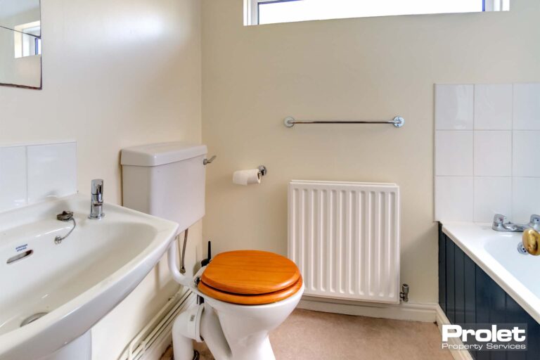 Downstairs bathroom with toilet, sink, and shower over bath