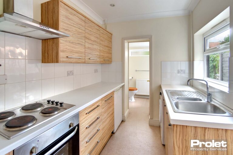 Kitchen with pale wood effect cabinets, and white worktops.