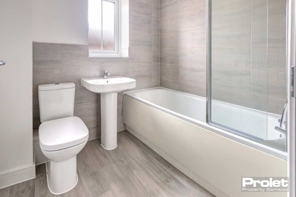 Bathroom with laminate flooring, white suite with shower over bath