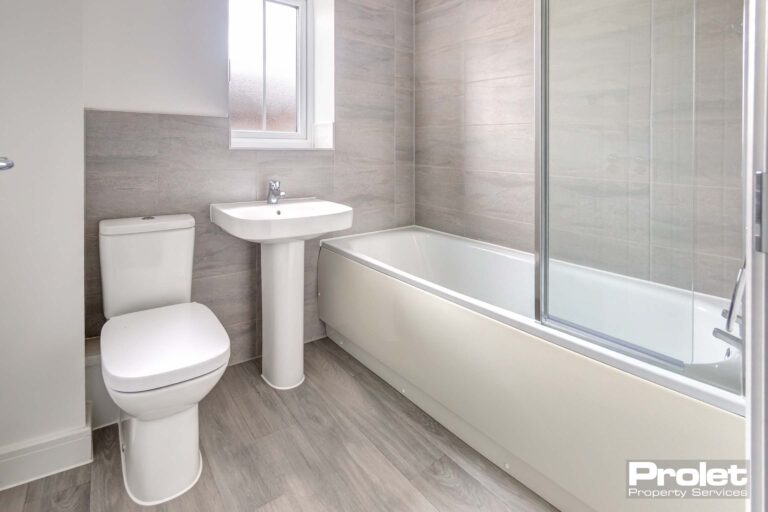 Bathroom with laminate flooring, white suite with shower over bath