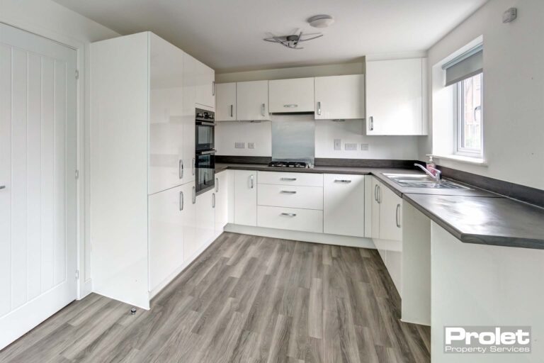 Grey laminate floor to kitchen with white units and grey work top. Integrated double oven and fridge freezer