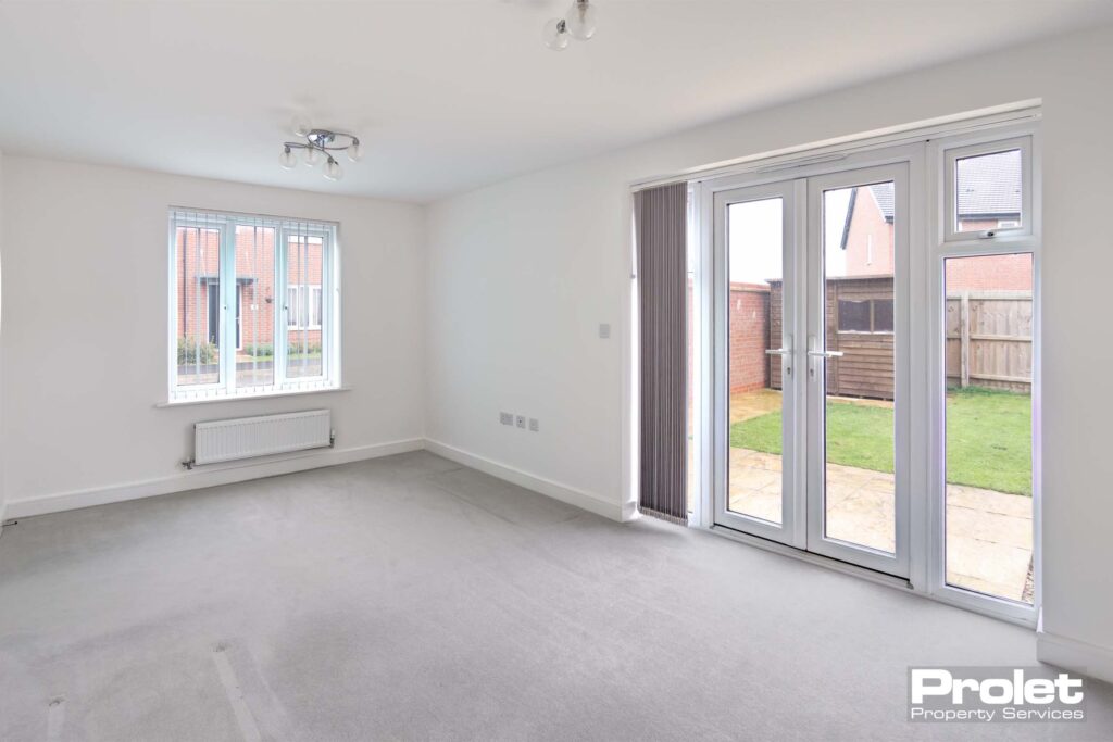 White walls with grey carpets and french doors to rear garden.