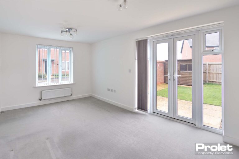 White walls with grey carpets and french doors to rear garden.