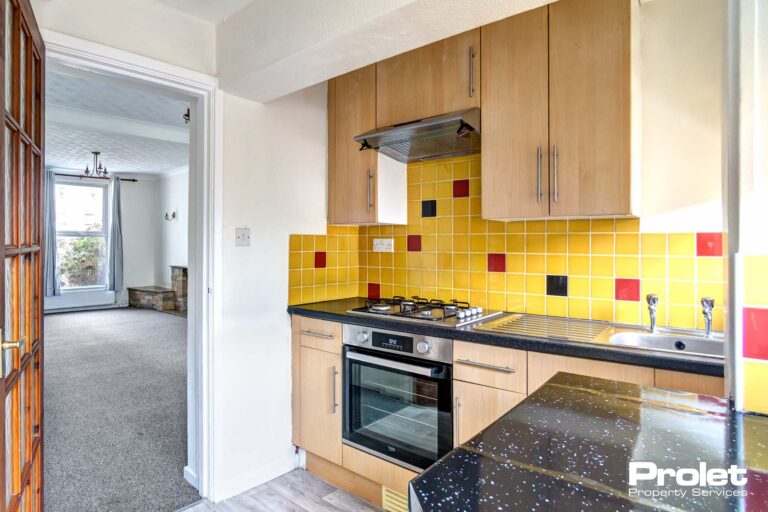 Kitchen with yellow backsplash, wooden cabinets, and black stone worktops