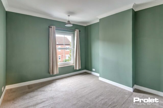 Double bedroom with green walls and light grey carpet