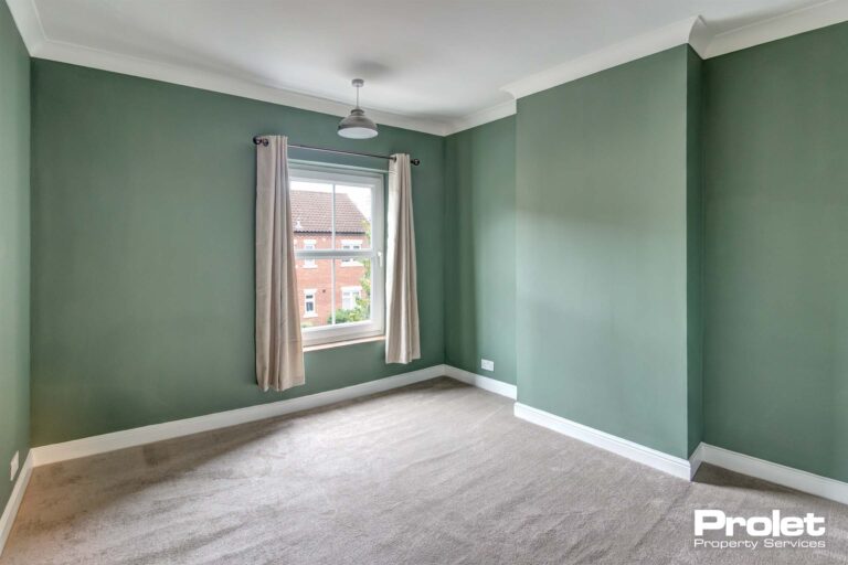 Double bedroom with green walls and light grey carpet