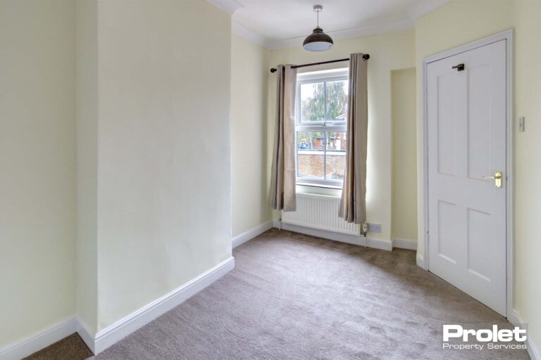 Bedroom with pale lemon coloured walls, and light grey carpet