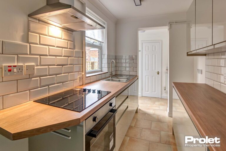 Kitchen with oven and hob, rear lobby, wooden worktops, tiled floor, and white cabinets