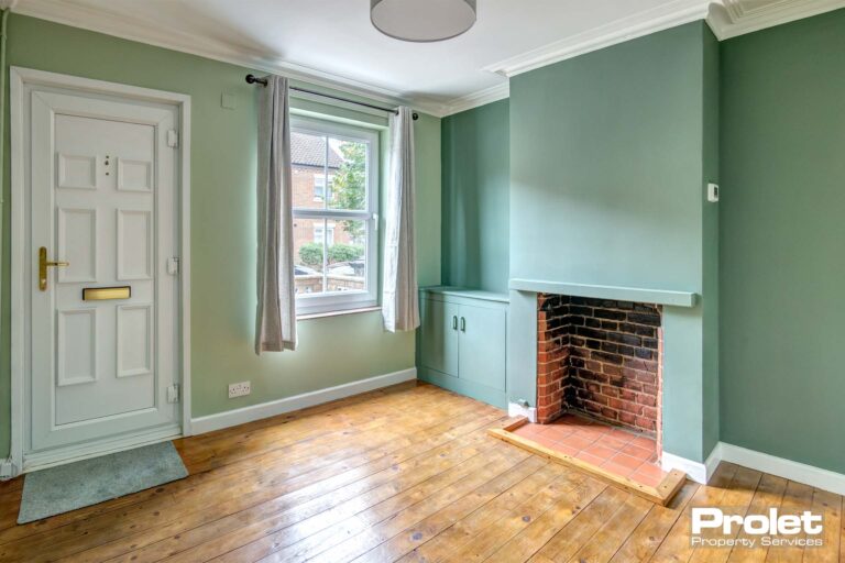 Lounge with stripped floorboards, green walls, and fireplace