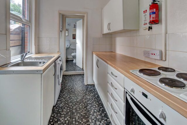 Kitchen with white cabinets, wood effect wotktop, and tiled floor