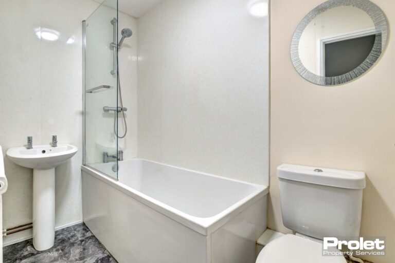 White bathroom suite with shower over bath and mirror over sink