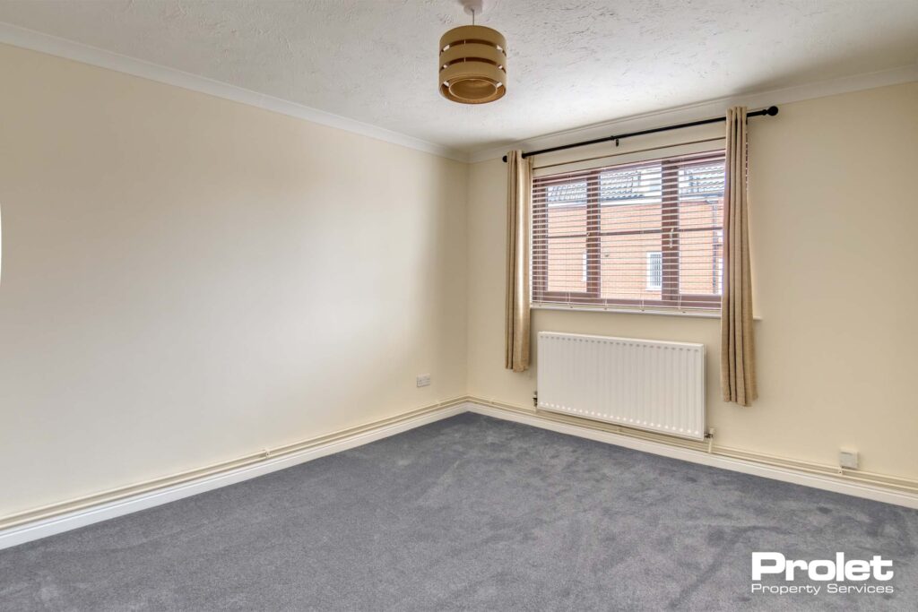 Grey carpets, magnolia walls and gas central heating with radiator under window